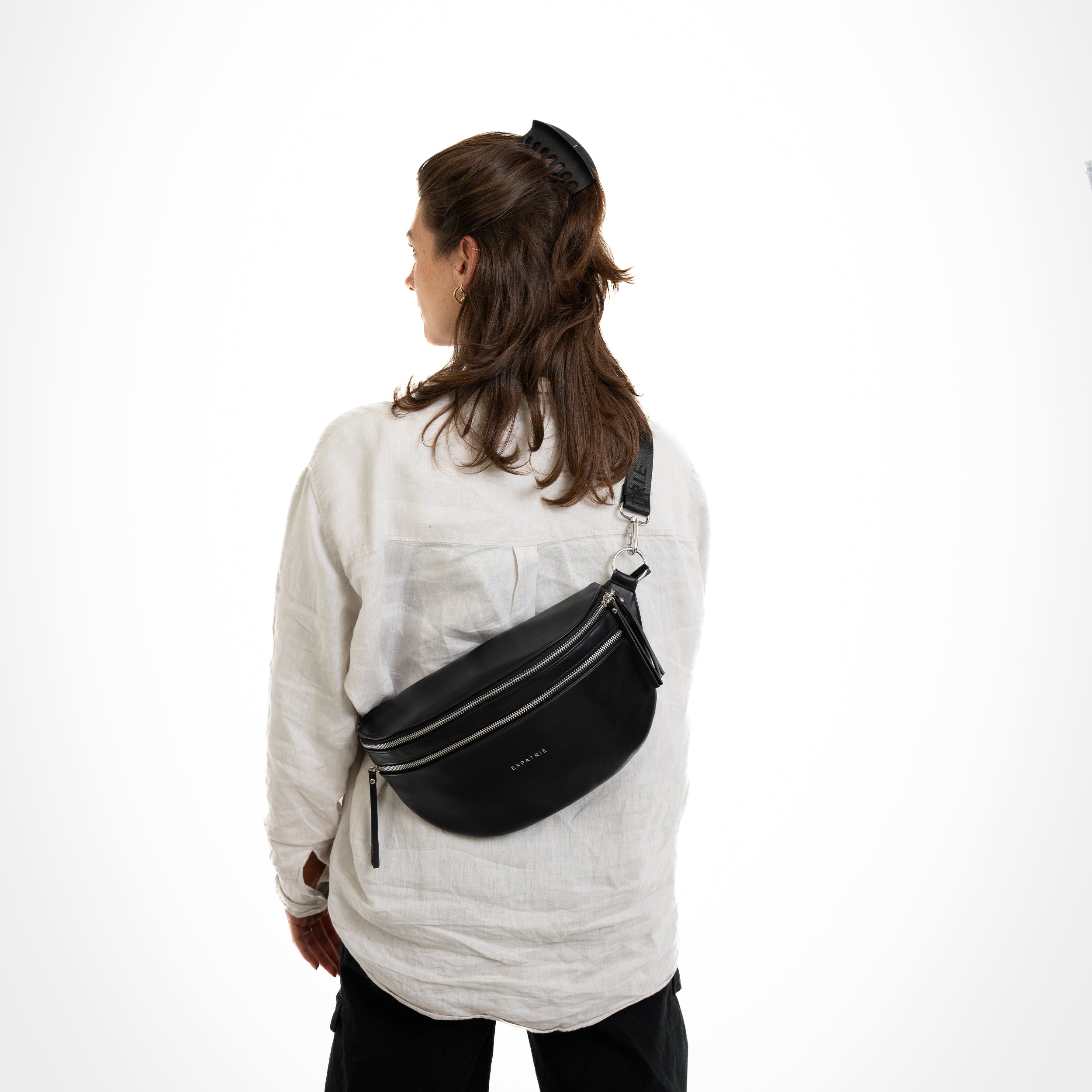 Frau trägt schwarze Leder-Bauchtasche 'Alice Large' über die Schulter, Rückansicht